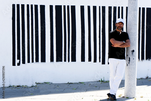 Foto A tall, stylish, dark-haired, thin, 40-year-old white man with a beard is wearing white pants, black shoes, a black polo shirt