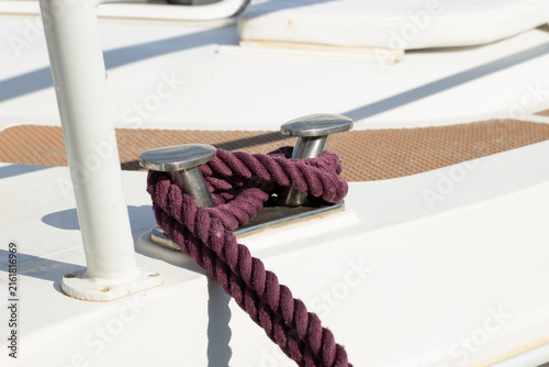 Quadro su tela Purple mooring rope secured around stainless steel cleat on a white yacht deck w