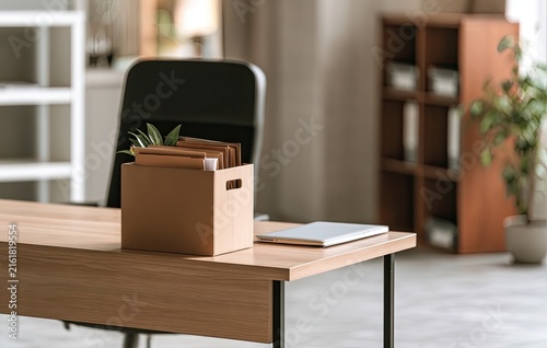 Cardboard box with files and laptop on a wooden desk in an office