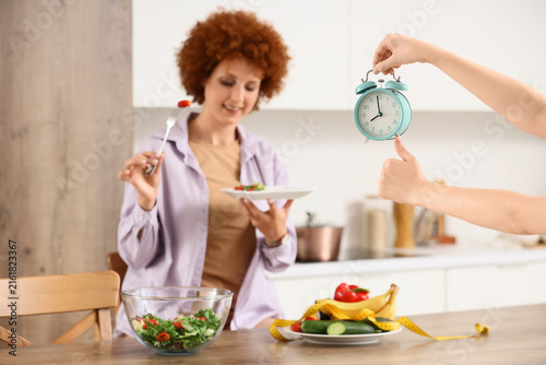 Healthy eating and time management for diet, woman with salad and alarm clock...