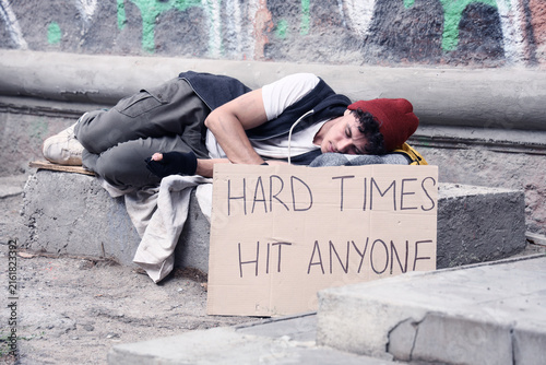 Bild auf Leinwand Homelessness and poverty crisis, young man sleeping on the street with a cardboa