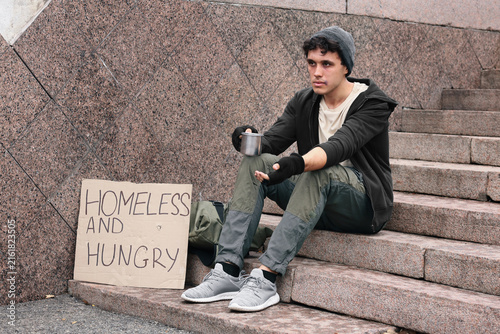 Картината върху платно Homelessness and poverty crisis, young man begging for money on city steps with