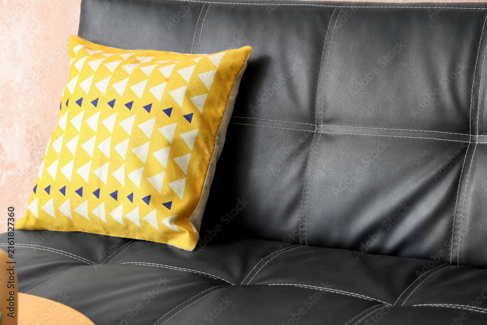 Fototapeta premium Home decor and interior design, yellow geometric pattern cushion on a black leather sofa, modern living room furniture