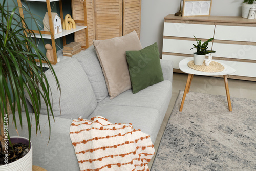 Interior of stylish living room with grey sofa, table and commode