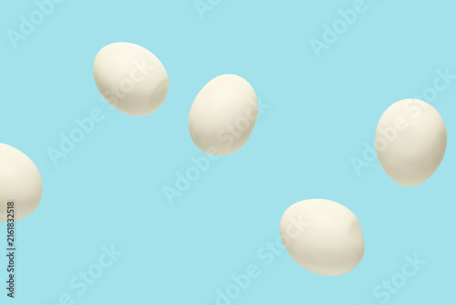 Foto Flying many boiled chicken eggs on blue background