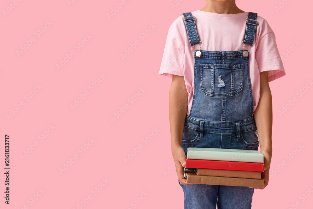 Naklejka premium Little girl with stack of books on pink background