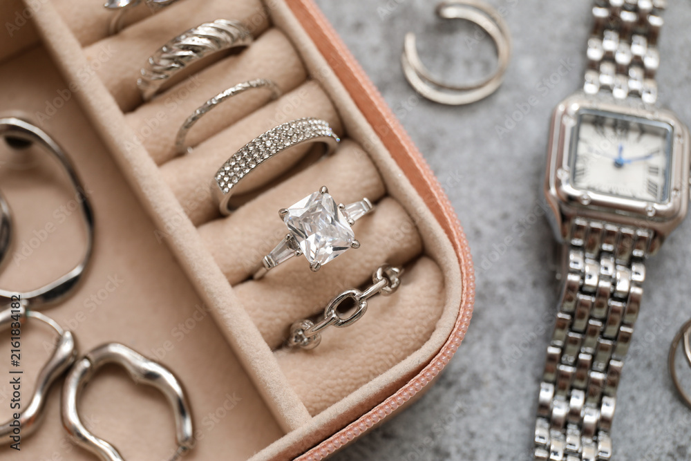Fototapeta premium Open organizer with different silver jewelry and wristwatch on grey grunge background, closeup