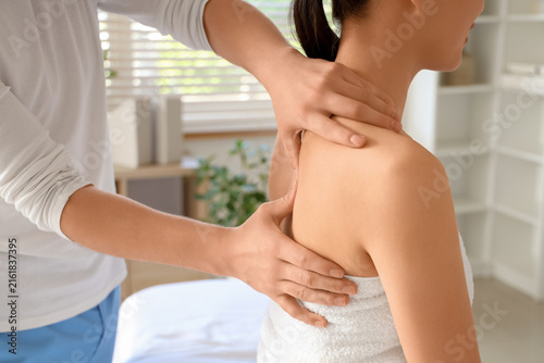 Male therapist massaging young womans back in spa salon, closeup