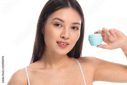 Young Asian woman with jar of facial cream on white background, closeup