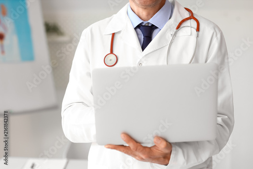 Mature doctor with laptop in medical office, closeup