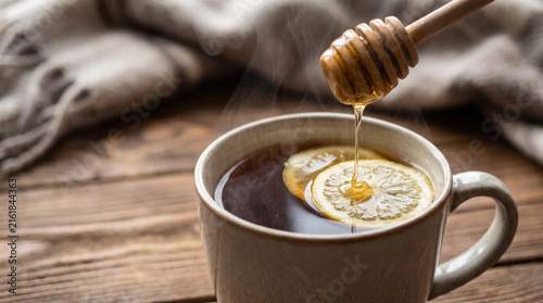 Warm drink in a cup with honey and lemon on a wooden table