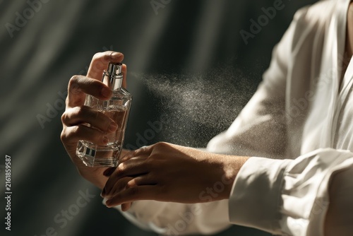 Hand sprays fine mist of perfume from elegant glass bottle