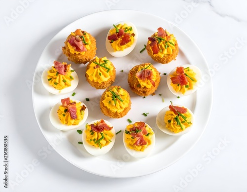 White plate with garnished deviled eggs and fried egg bites