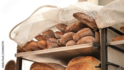 Artisan bread loaves on bakery shelves, keeping warm under a white mesh cloth