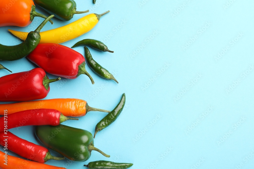 Fototapeta premium Many different colorful peppers on light blue background, flat lay. Space for text
