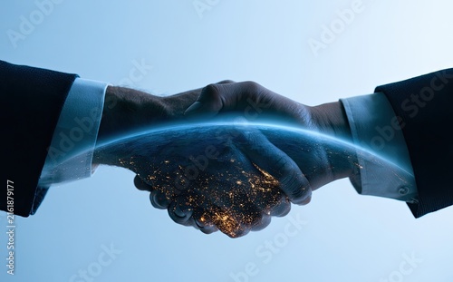 Two hands clasped in agreement, glowing globe beneath