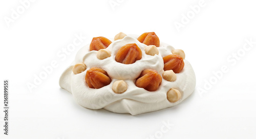 Distant shot of 5 to 10 dried persimmon pieces and macadamia nuts half-submerged in thick white milk cream