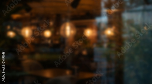 Abstract blurred background of cozy cafe interior with warm hanging lights.