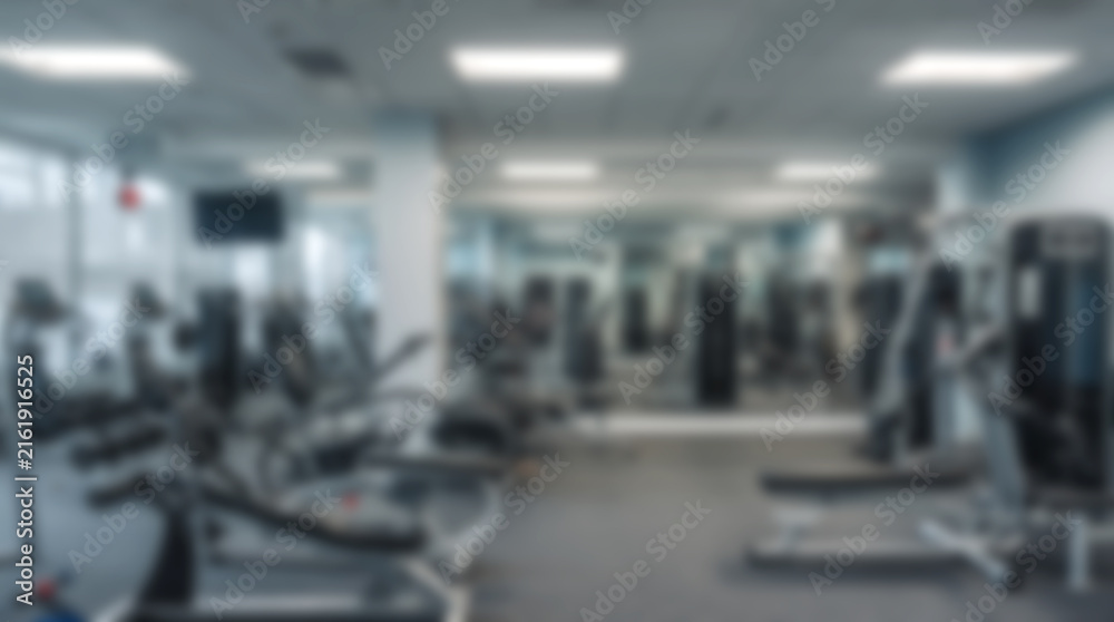 Fototapeta premium Blurred background of modern gym interior with fitness equipment and workout machines.