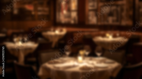 Blurred background of an elegant fine dining restaurant interior with candlelit tables.