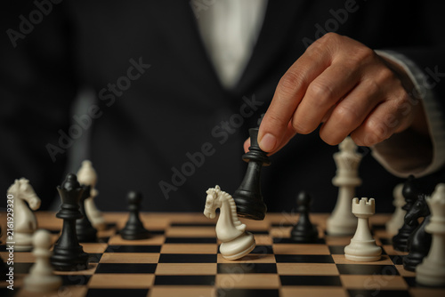 Картината върху платно business hand holding black chess king taking white knight, strategy concept