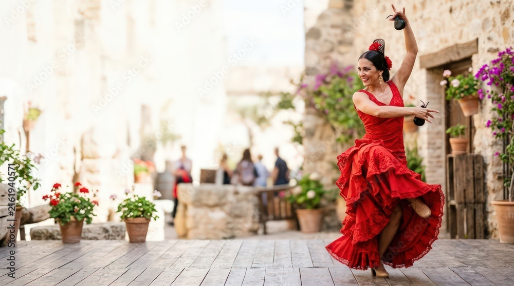 Obraz premium Spanish Woman in Red Dress Performing Flamenco Dance Outdoors with Castanets