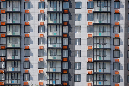 Close-up view of a modern apartment building facade with repeating windows and balconies, creating a geometric architectural background. Ust-Kamenogorsk (Kazakhstan)