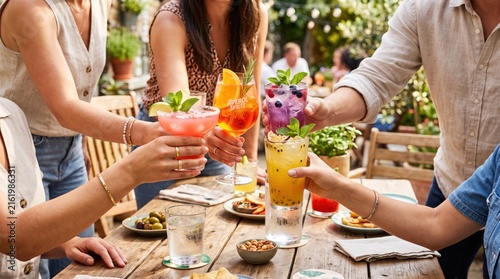 Friends toasting with colorful cocktails at outdoor party, summer celebration and social gathering concept with refreshing drinks and happy people