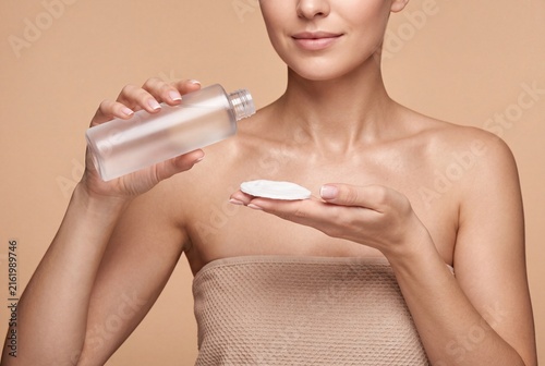 Woman applying skincare product to a cotton pad
