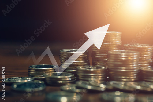 Rising arrow over stacked coins illustrates financial growth, increasing profits, investment returns, wealth building, savings, business success, and positive economic performance.
