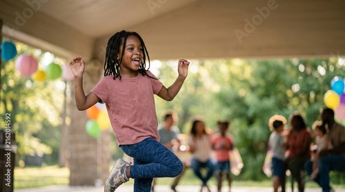 Joyful Dancer at Outdoor Gathering: A young Black girl with dreadlocks joyfully dances at an outdoor party, her expression brimming with pure delight.