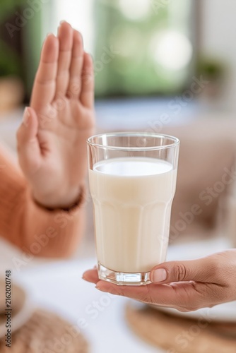 Woman refusing a glass of milk, representing dietary restrictions and healthy choices