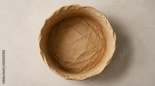 Top view of a handmade brown paper bowl on a neutral background, perfect for eco-friendly product packaging mockups, sustainable brand identity, and organic texture design element.