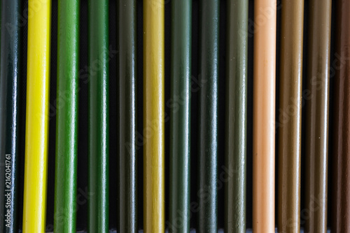 close-up of green and brown colored pencils neatly lined up in pencil case, concept of creativity, drawing, education and art supplies