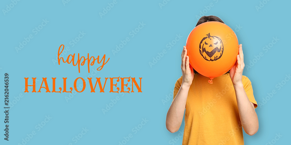 Naklejka premium Halloween. Child holds cheerful Halloween balloon while smiling in vibrant setting