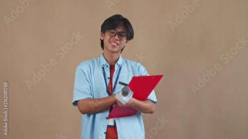  Asian male reporter holding microphone while taking notes on red clipboard in studio background