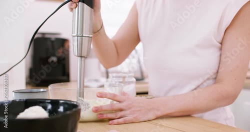 Blending food. Preparing meal. Woman chef hand mixing white cottage cheese in bowl on kitchen countertop with modern electric equipment.