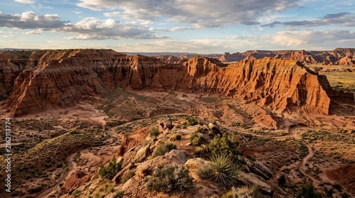 Breathtaking Panoramic View of Eroded Red Sandstone Cliffs and Arid Desert Valley Under a Vibrant Cloudy Sky