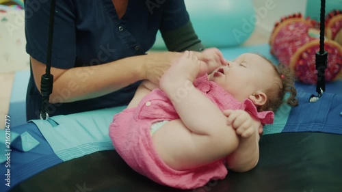 Therapist assisting a baby with special needs during a physical therapy session using a sensory swing for development