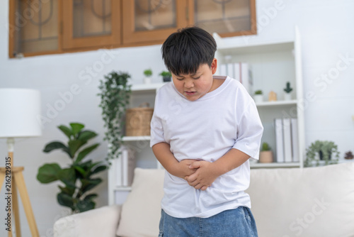 Foto Portrait of sick unhappy little child asian boy touching belly stomach with suff