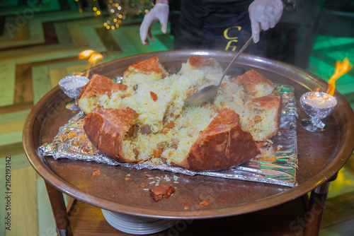 фотографія Chef cutting traditional shah plov baked in golden lavash crust during a fiery presentation on a tray