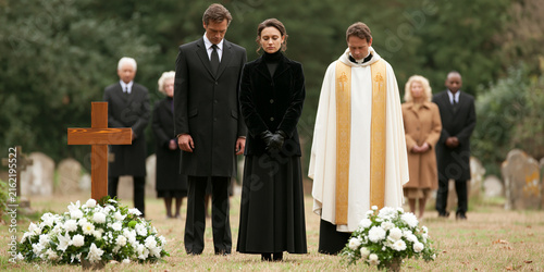 A somber funeral service takes place in a cemetery, with mourners dressed in black gathered around a priest. A wooden cross and floral arrangements mark a gravesite.
