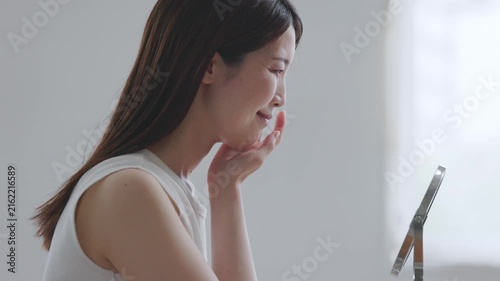 鏡を見て口元と頬の状態を確認する女性