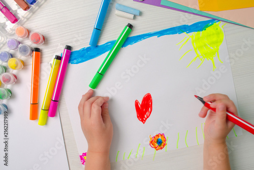 Child paints heart with red marker Top view Creative art activity promoting imagination, fine motor skills, artistic expression, and early childhood learning Cognitive development