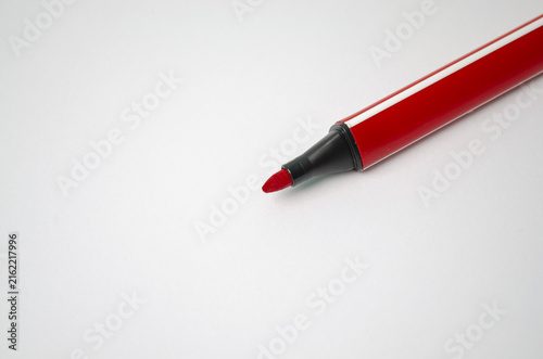 Red marker pen lying on white paper surface with copy space, perfect for school supplies, office stationery, education, editing, drawing, and business concept projects.