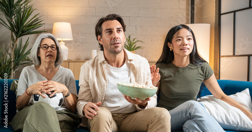 Fotografie Family members watching football on tv, reacting to an exciting moment with popc