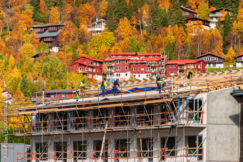 Construction workers in safety gear working on a multi‑story building surrounded by scaffolding