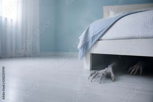 Creepy hands reaching from under bed in bedroom, childhood fear and nightmare horror concept