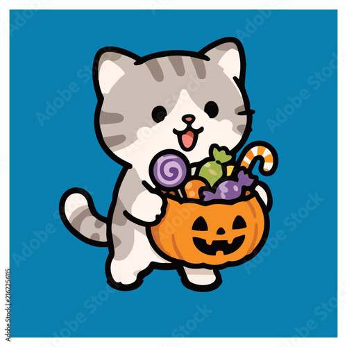Foto Cute gray and white cat holding a jack o lantern basket filled with colorful candy for Halloween trick or treating