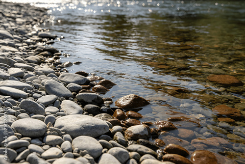 Smooth river stones and pebbles along a flowing stream water edge in nature